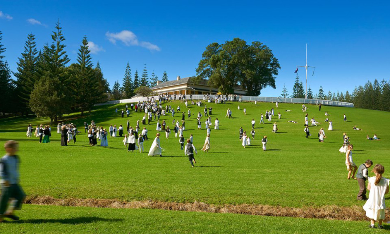 Children roll down the grassy hill of Government House on Norfolk Island's Bounty Day